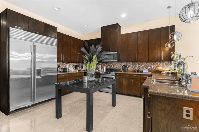 a kitchen with stainless steel appliances kitchen island granite countertop a refrigerator a stove and a sink