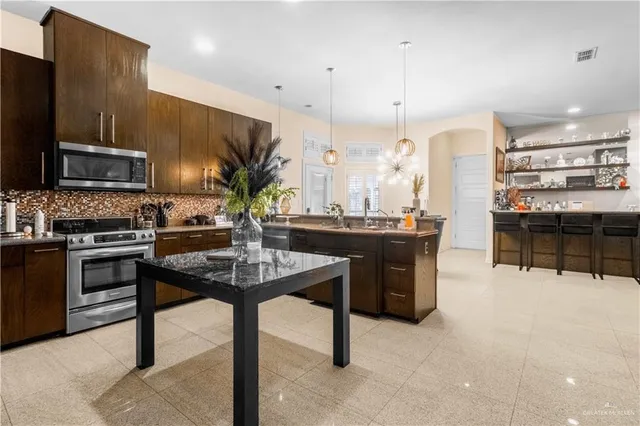 a kitchen with stainless steel appliances kitchen island granite countertop a stove a sink a refrigerator and a microwave