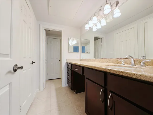 a bathroom with a granite countertop sink a light fixture and a mirror