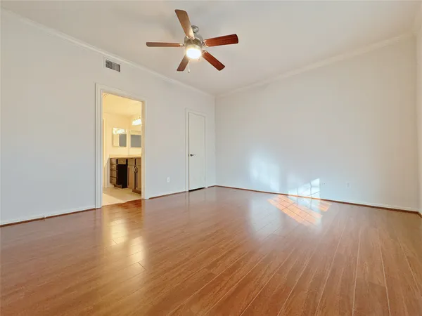 an empty room with wooden floor and ceiling fan