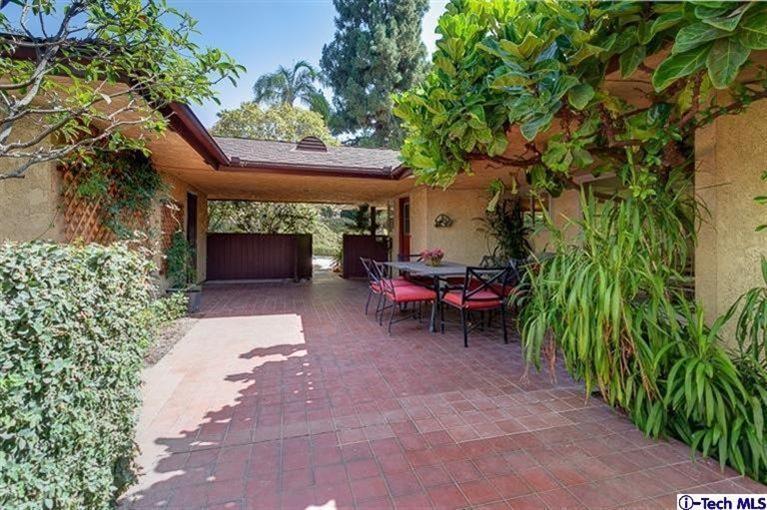 2238 Rim Road Bradbury, CA 91008 - Photo 24 of 27 a view of a patio with table and chairs under an umbrella with large trees