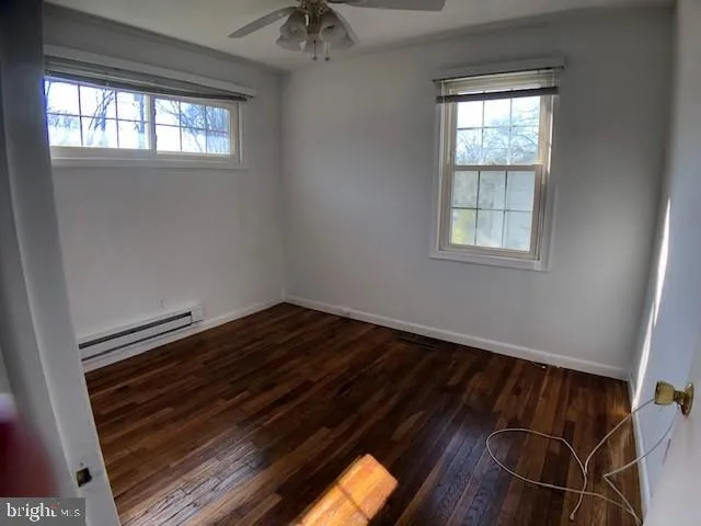 an empty room with wooden floor fan and windows