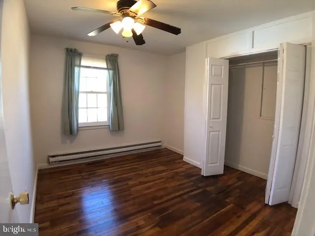 an empty room with wooden floor closet and windows
