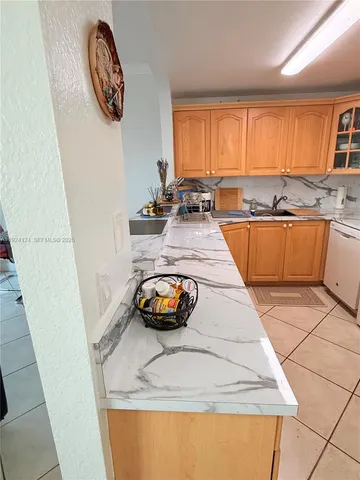 a view of a kitchen with kitchen island a large window a sink a counter and lots of appliances