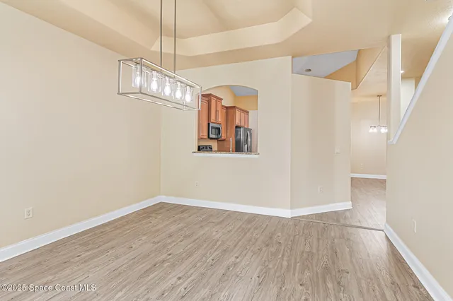 a view of a hallway with wooden floor and chandelier