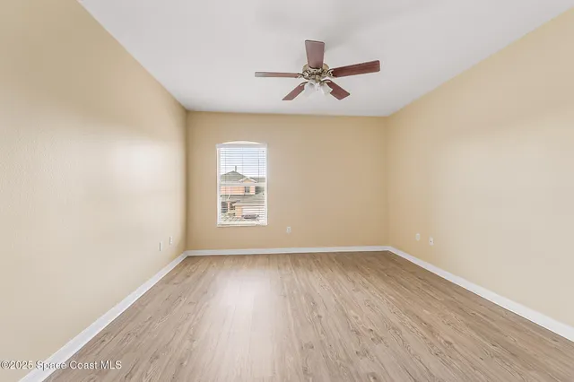 a view of an empty room with window and a ceiling fan