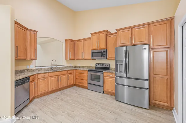 a kitchen with stainless steel appliances granite countertop a refrigerator stove top oven and sink