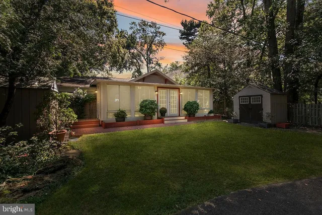a backyard of a house with table and chairs plants and large tree