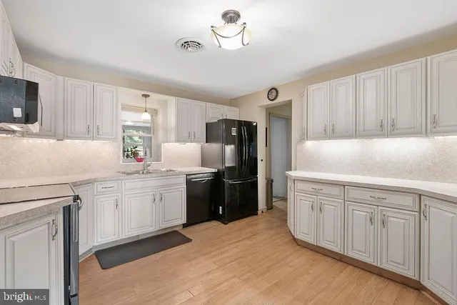 a kitchen with granite countertop a sink stainless steel appliances and white cabinets
