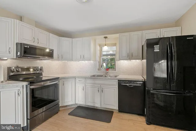a kitchen with stainless steel appliances a stove a sink and a refrigerator