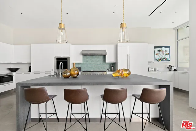 a kitchen with stainless steel appliances a counter and chairs