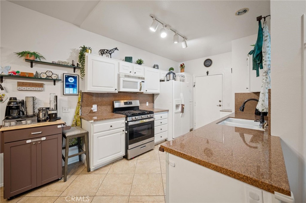 20000 Plum Canyon Road, Unit 316 Saugus, CA 91350 - Photo 8 of 27 a kitchen with granite countertop a sink stove and refrigerator