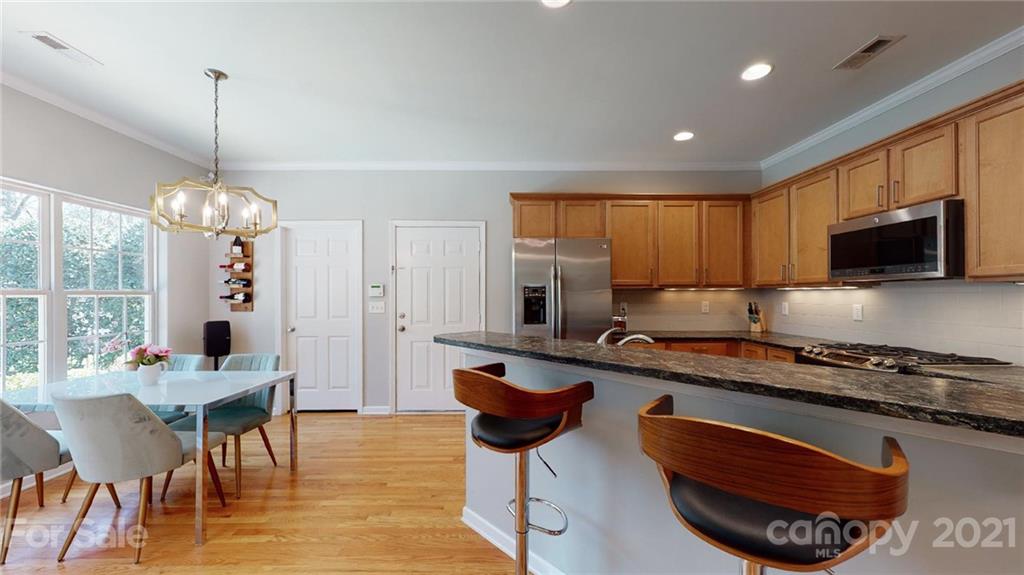 5725 Brookhaven Road Charlotte, NC 28210 - Photo 11 of 39 a kitchen with stainless steel appliances granite countertop a stove top oven a sink a dining table and chairs