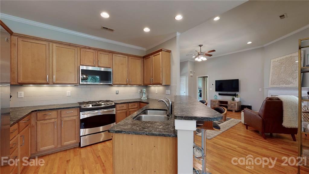 5725 Brookhaven Road Charlotte, NC 28210 - Photo 16 of 39 a kitchen with stainless steel appliances granite countertop a stove top oven a sink dishwasher and a microwave with wooden floor