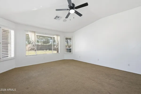 an empty room with a chandelier fan and windows