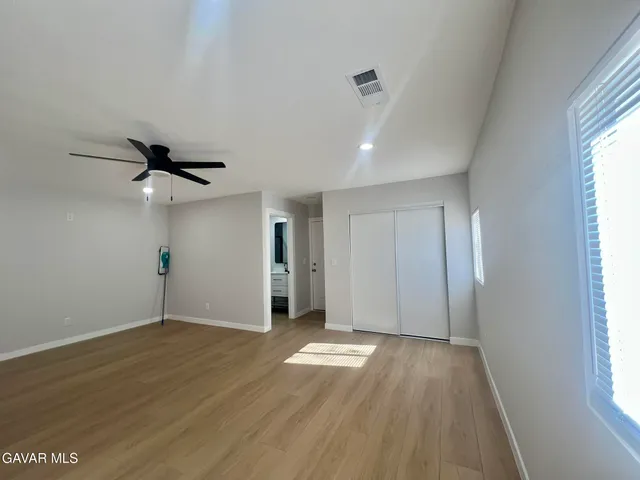 a view of empty room with wooden floor and fan