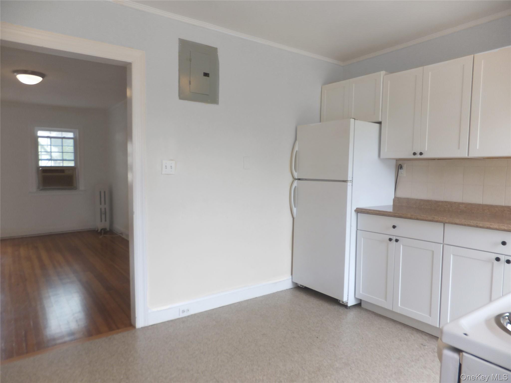 107 Kensington Road, Unit 5 Bronxville, NY 10708 - Photo 4 of 17 Kitchen featuring white appliances, white cabinets, electric panel, ornamental molding, and tasteful backsplash