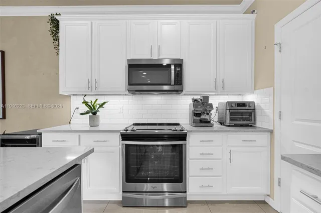 a kitchen with white cabinets and black appliances
