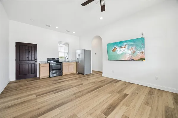a view of kitchen with stainless steel appliances wooden floor and chair