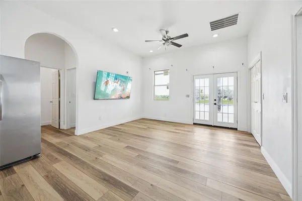 a view of an empty room with window and wooden floor
