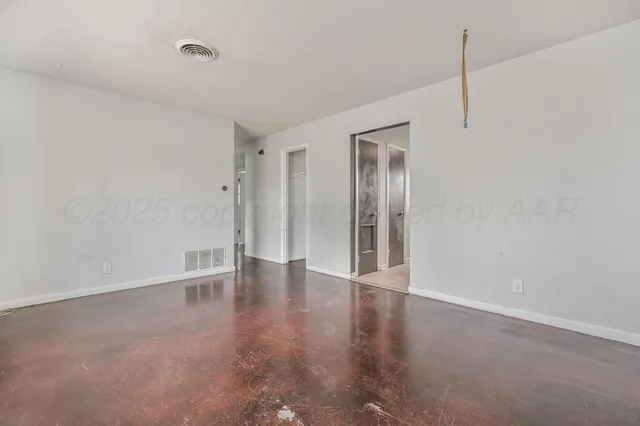 a view of an empty room with closet and a window