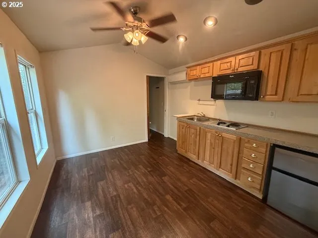 a kitchen with stainless steel appliances granite countertop a refrigerator a sink dishwasher a stove and white countertops with wooden floor