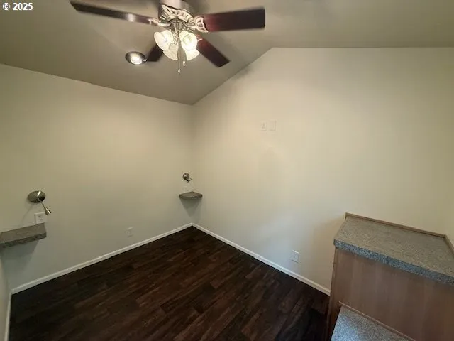 a room with a hanging light and hardwood floor