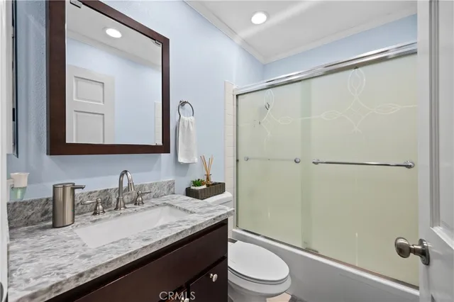 a bathroom with a granite countertop sink mirror vanity and toilet