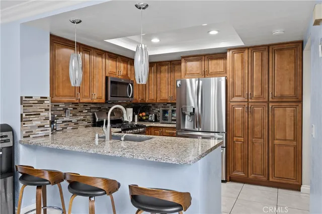 a kitchen with stainless steel appliances granite countertop a refrigerator a sink and wooden cabinets