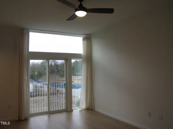 an empty room with a ceiling fan and a window