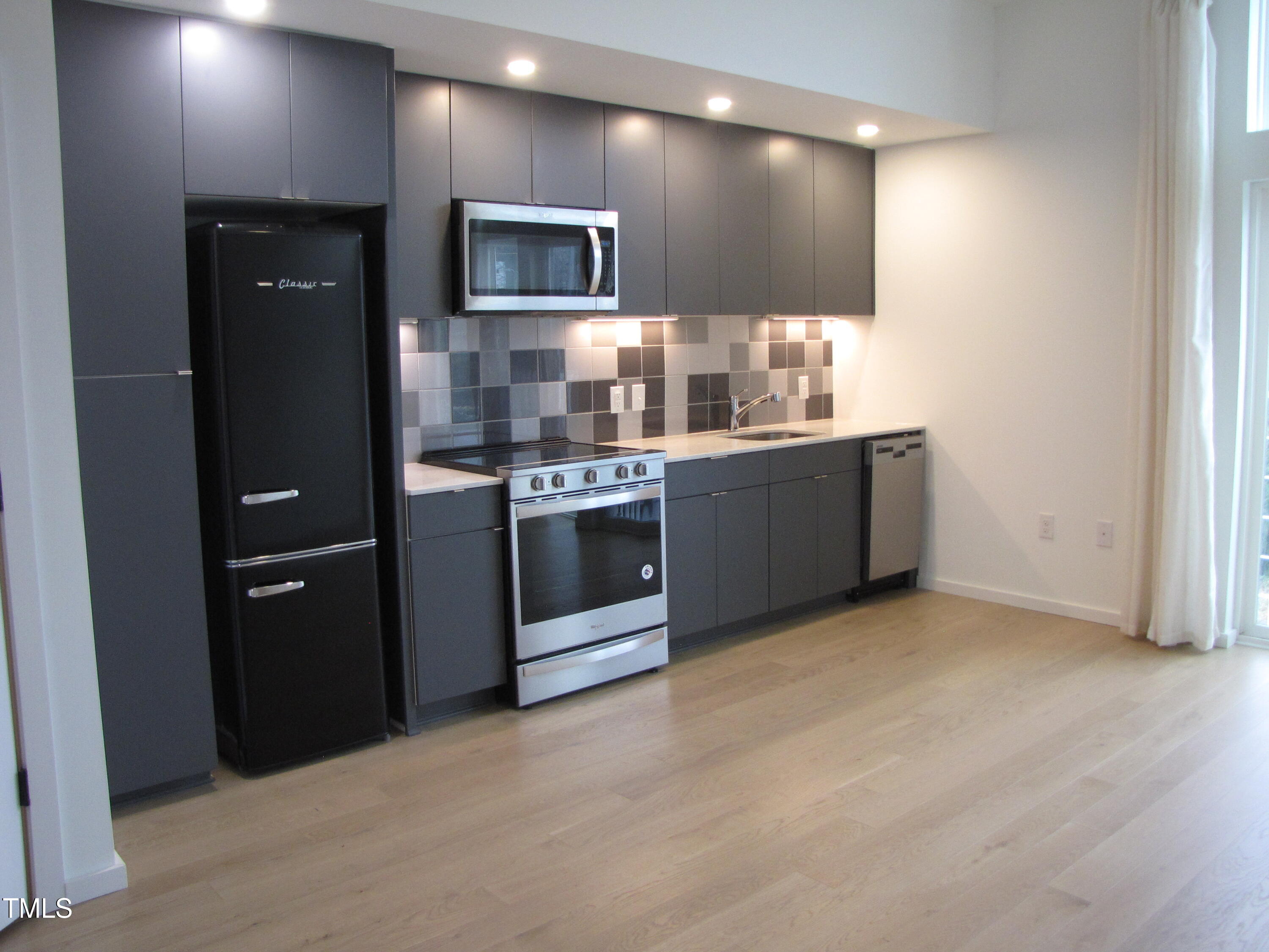600 South Duke Street, Unit 23 Durham, NC 27701 - Photo 6 of 19 a kitchen with stainless steel appliances granite countertop a refrigerator a stove a sink and a microwave