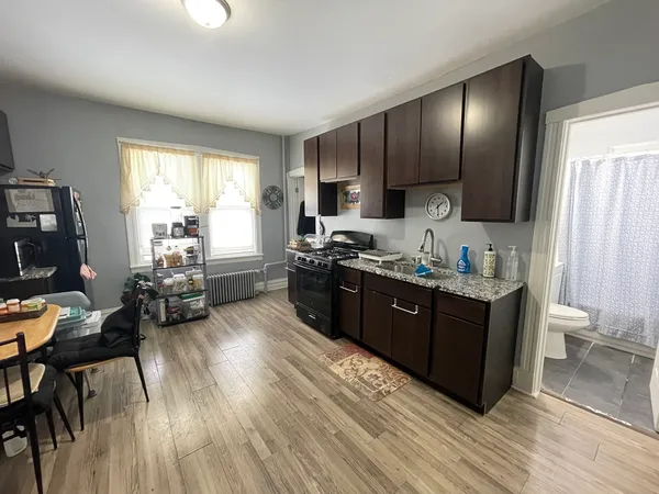 a kitchen with stainless steel appliances granite countertop wooden cabinets a sink dishwasher a stove and a refrigerator with wooden floor