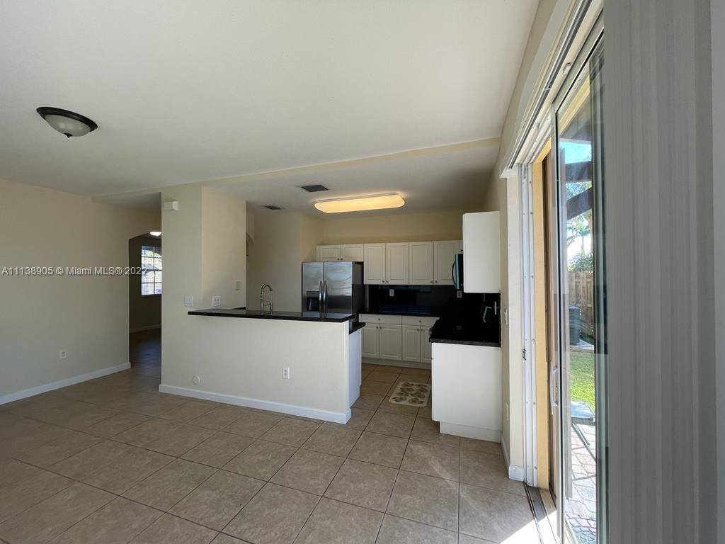 9323 Southwest 227th Street, Unit 75 Cutler Bay, FL 33190 - Photo 14 of 44 a large white kitchen with a white countertops a stove and a refrigerator with wooden floor