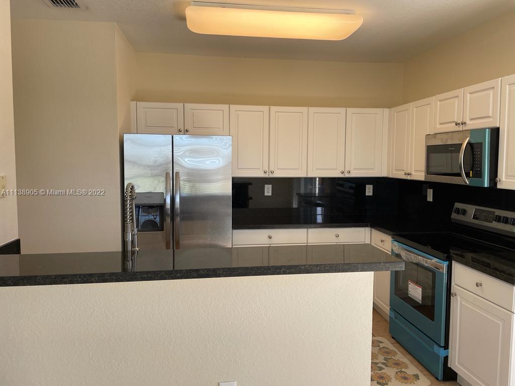 9323 Southwest 227th Street, Unit 75 Cutler Bay, FL 33190 - Photo 15 of 44 a kitchen with stainless steel appliances a refrigerator a stove a microwave and cabinets