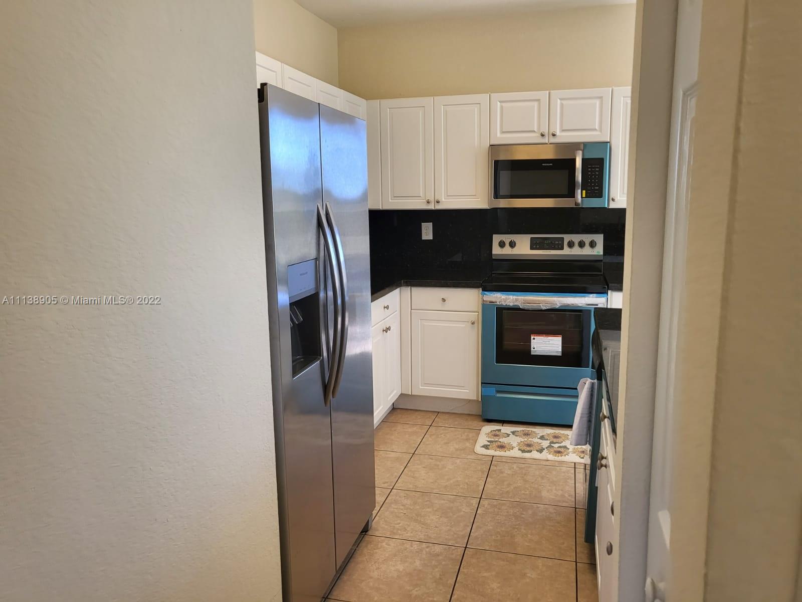 9323 Southwest 227th Street, Unit 75 Cutler Bay, FL 33190 - Photo 17 of 44 a kitchen with stainless steel appliances a stove a microwave and a refrigerator