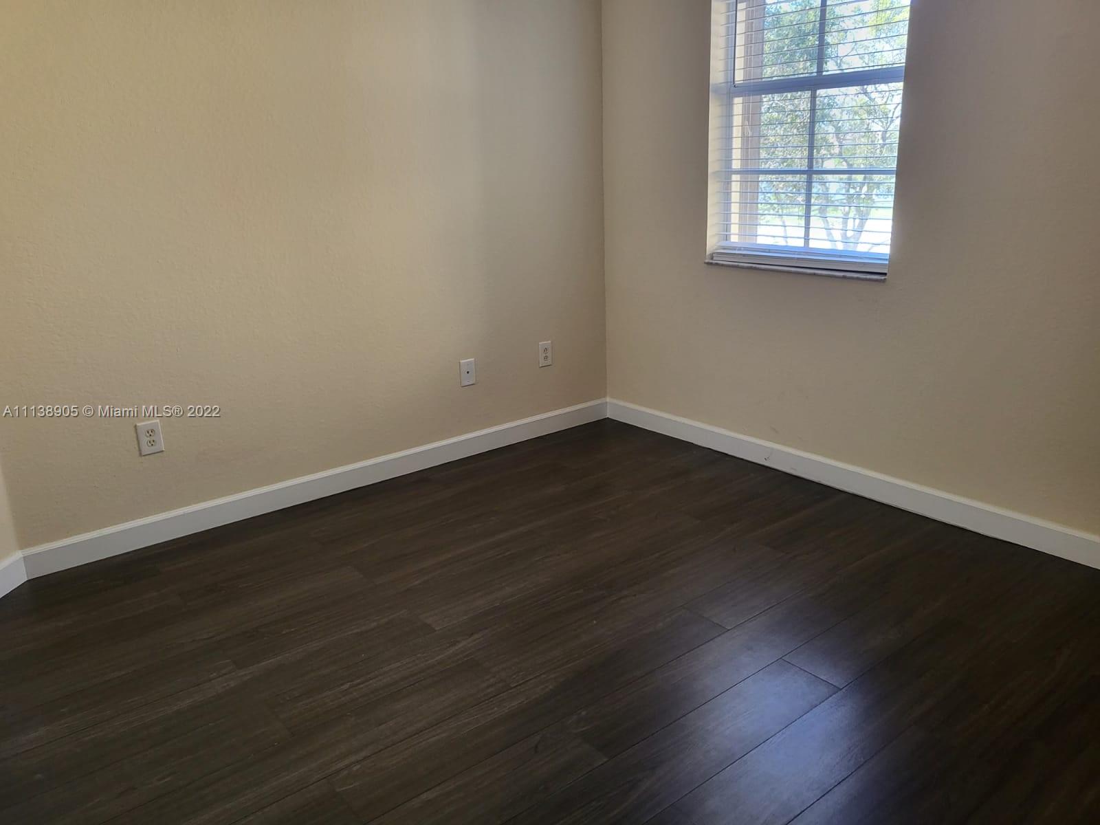 9323 Southwest 227th Street, Unit 75 Cutler Bay, FL 33190 - Photo 23 of 44 an empty room with wooden floor and windows in it