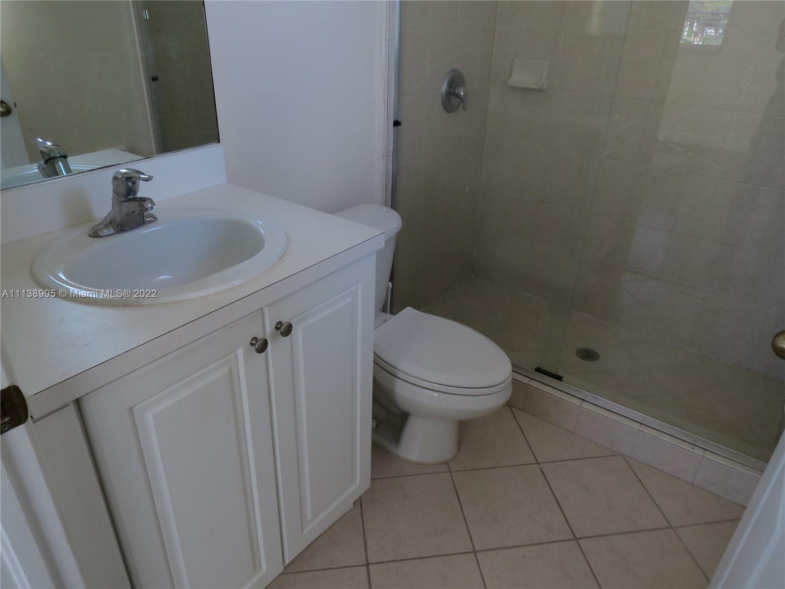 9323 Southwest 227th Street, Unit 75 Cutler Bay, FL 33190 - Photo 32 of 44 a bathroom with a sink a toilet and a mirror