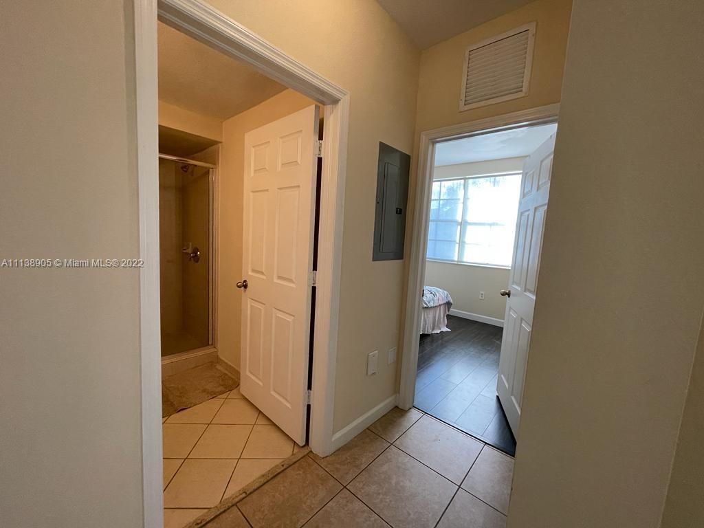 9323 Southwest 227th Street, Unit 75 Cutler Bay, FL 33190 - Photo 9 of 44 a view of a hallway with wooden floor and a bathroom