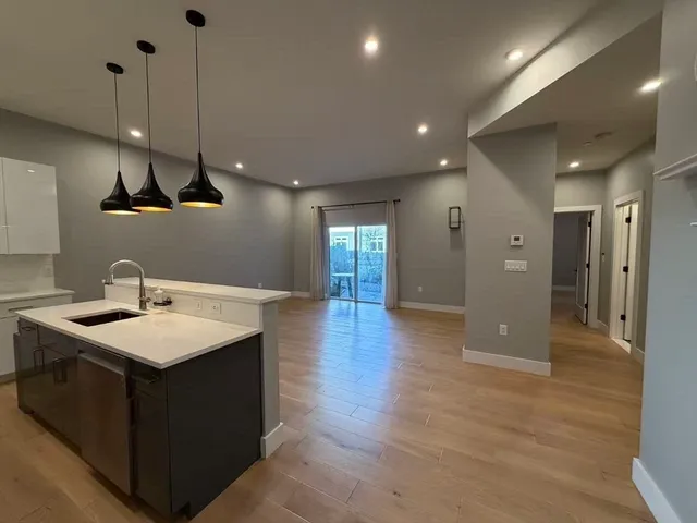 a large kitchen with stainless steel appliances a large counter top a stove a sink and a refrigerator