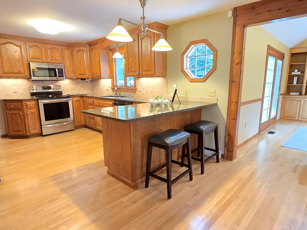 42 Wayside Lane Ashland, MA 01721 - Photo 19 of 40 a kitchen with stainless steel appliances granite countertop a stove a sink dishwasher and a refrigerator with wooden floor