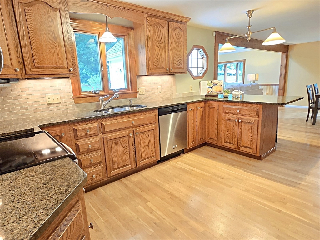 42 Wayside Lane Ashland, MA 01721 - Photo 21 of 40 a kitchen with granite countertop a sink a stove a oven cabinets and wooden floor