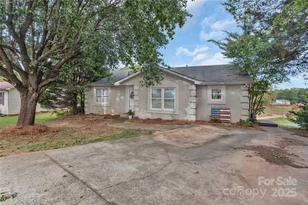 a view of a house with a yard and large tree