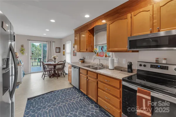 a kitchen with stainless steel appliances granite countertop a stove top oven a sink dishwasher a dining table and chairs with wooden floor