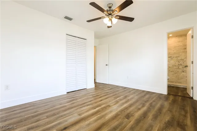 an empty room with wooden floor fan and windows