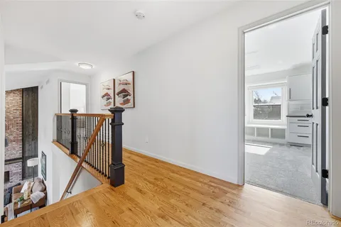 a view of a hallway with wooden floor and a bathroom