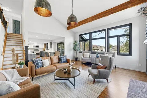 a living room with furniture a rug potted plant and a large window