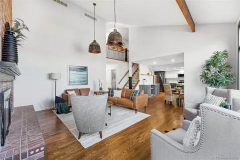 a living room with couches and a dining table with wooden floor
