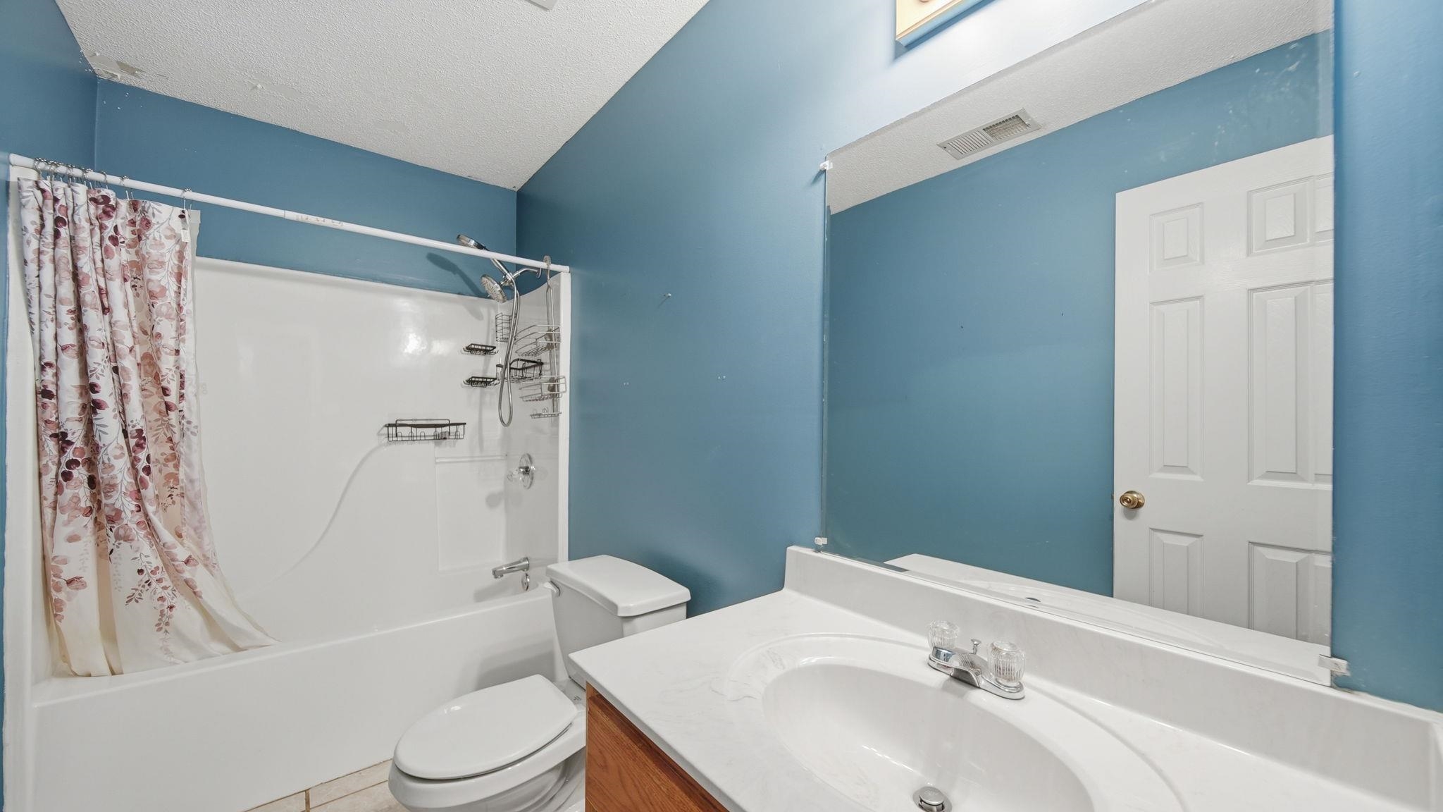 217 Rae Drive Munford, TN 38058 - Photo 26 of 40 Bathroom featuring a white bathtub and shower combination, a toilet, a vanity with a white countertop and integrated sink, and an expansive wall mirror