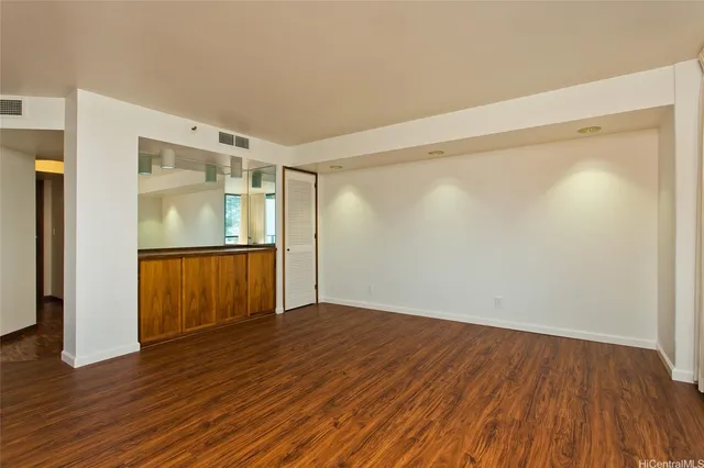 a view of an empty room with wooden floor and a window