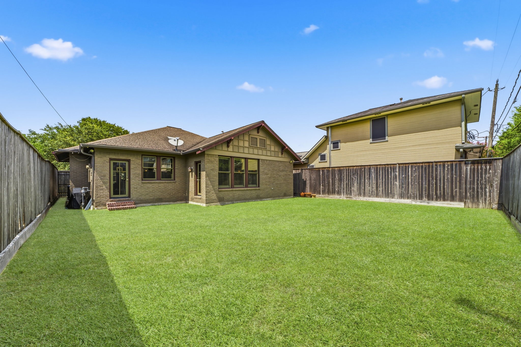 1521 Kipling Street Houston, TX 77006 - Photo 34 of 35 Spacious backyard with lush green lawn, privacy fence, and charming brick exterior, perfect for outdoor activities and relaxation.